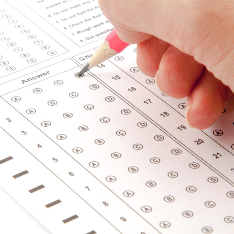 Mano che compila il foglio risposte di un test di ammissione a crocette.