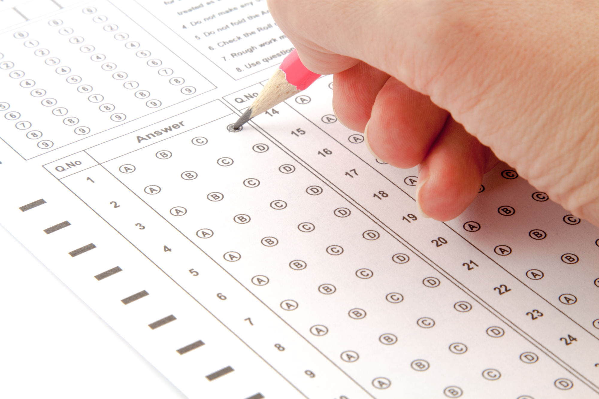 Mano che compila il foglio risposte di un test di ammissione a crocette.