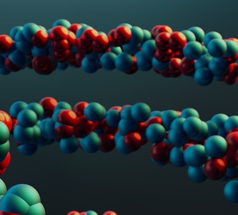 Sfondo a gradiente verde petrolio da sinistra (chiaro) a destra (scuro). In primo piano delle sfere rosse e verdi unite per creare la configurazione elettronica degli elementi.