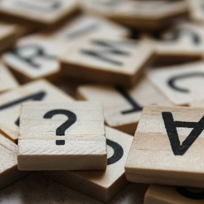 Tessere di legno con dei caratteri stampanti in nero. In primo piano c'è un punto interrogativo e una lettera a capovolta. I trucchi per superare i test a risposta multipla permettono di scartare le opzioni in eccesso e trovare velocemente la soluzione corretta.