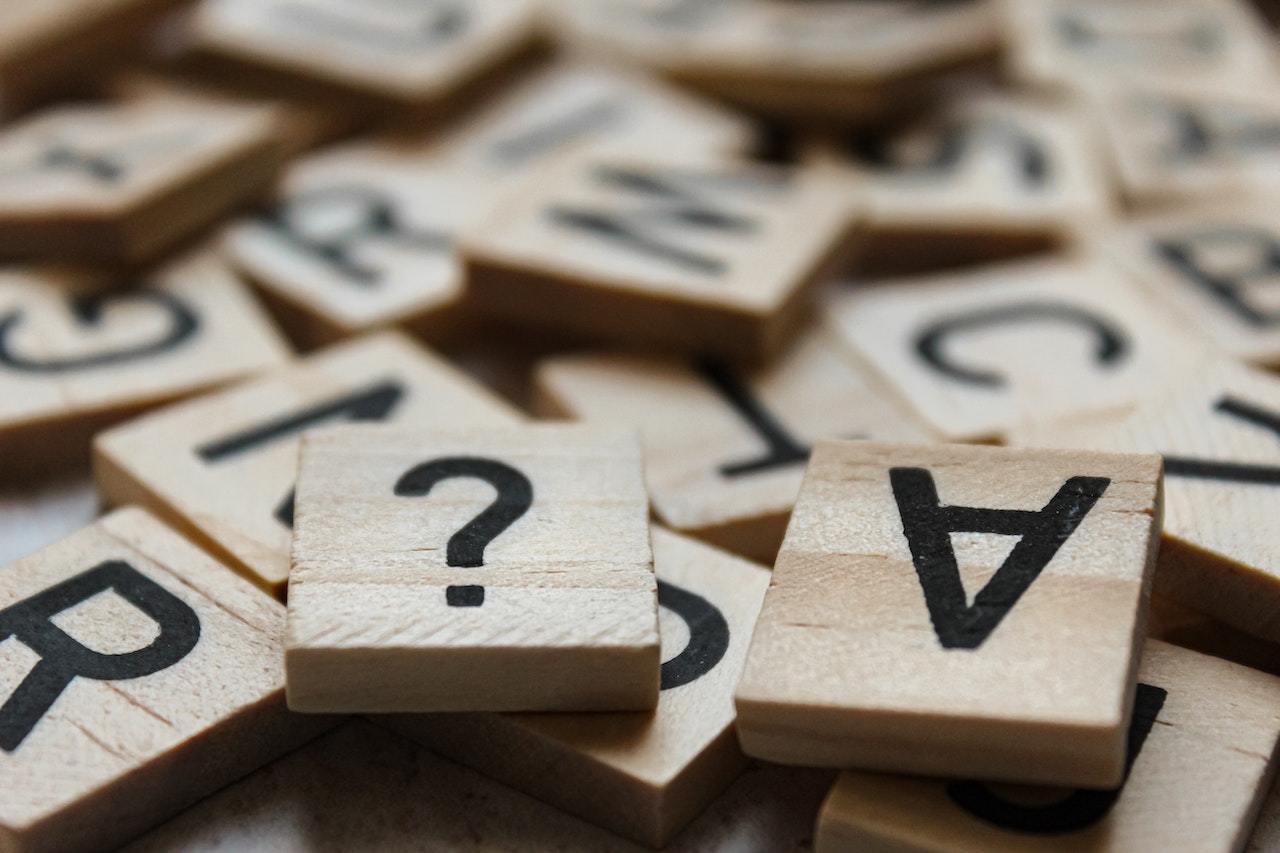 Tessere di legno con dei caratteri stampanti in nero. In primo piano c'è un punto interrogativo e una lettera a capovolta. I trucchi per superare i test a risposta multipla permettono di scartare le opzioni in eccesso e trovare velocemente la soluzione corretta.