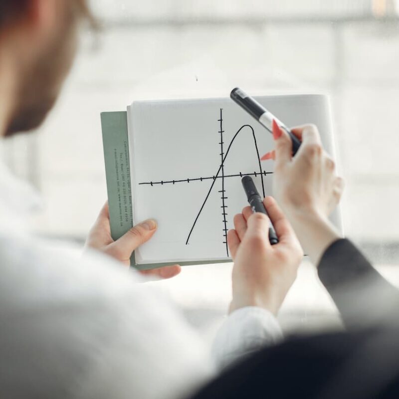 Il moto parabolico e le sue formule descrivono vari parametri dello spostamento di un oggetto lanciato in aria. Come mostrato dal grafico in foto la traiettoria può avere angoli diversi. Il grafico è disegnato con i pennarelli , che lo stanno puntando mentre sono tenuti in mano da due fisici di spalle e fuori fuoco.