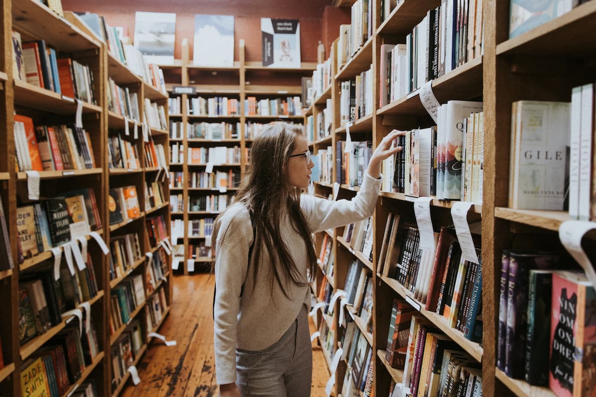 Studentessa in libreria mentre guarda i libri sugli scaffali.
