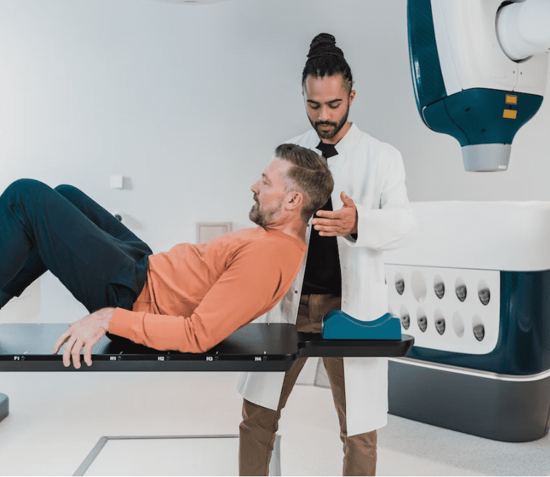 Tecnico Radiologo mentre aiuta un paziente a posizionarsi per effettuare delle analisi.