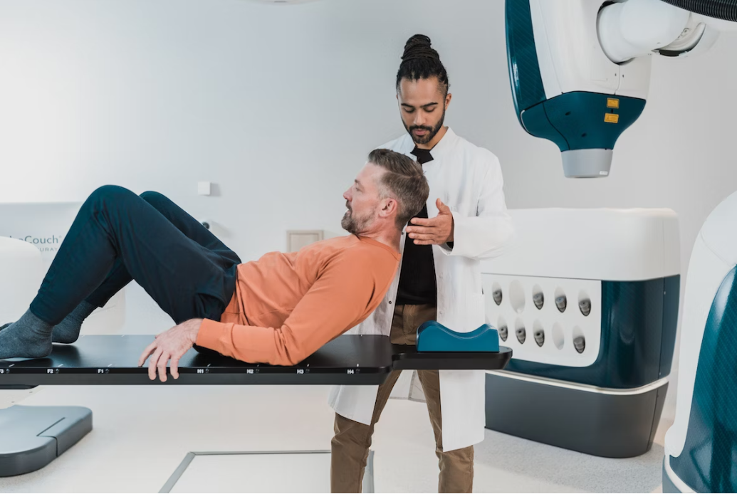 Tecnico Radiologo mentre aiuta un paziente a posizionarsi per effettuare delle analisi.