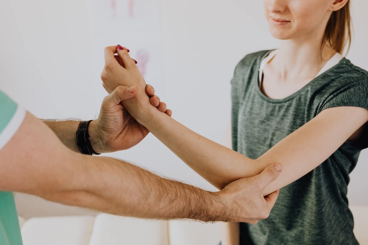 Fisioterapista mentre controlla il braccio di una paziente.