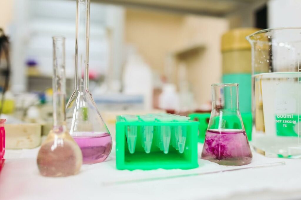 Tavolo di un laboratorio chimico con becher, ampolle e provette in primo piano