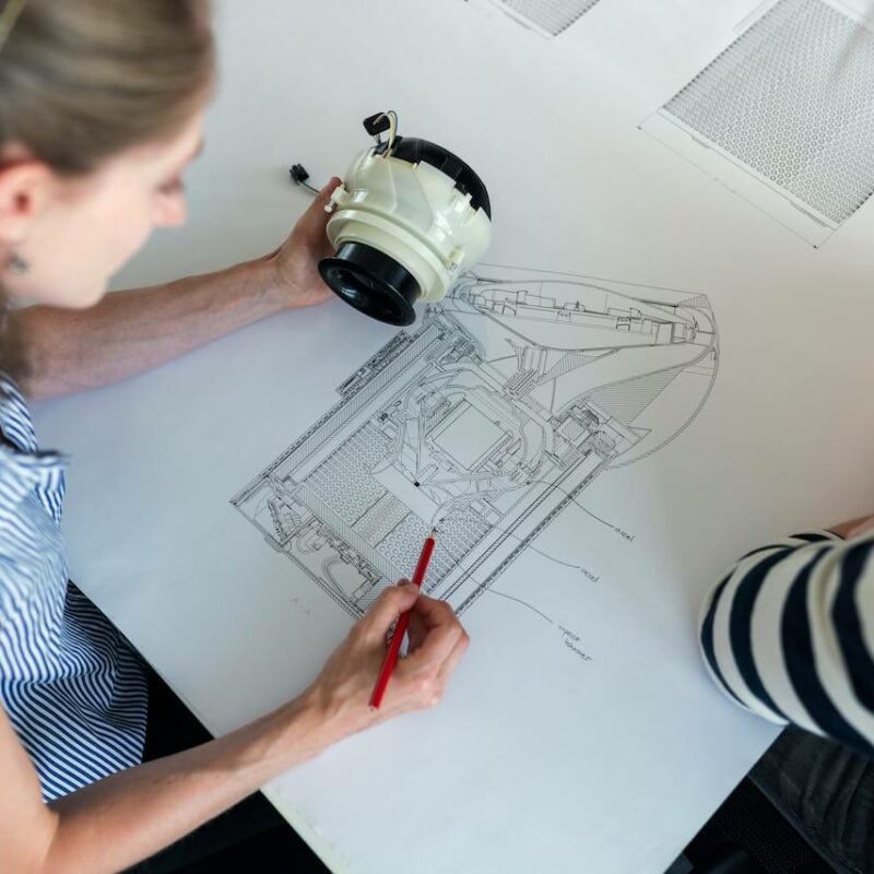 Ingegnere che analizza insieme a un collega la progettazione di un modello di un componente tecnologico.