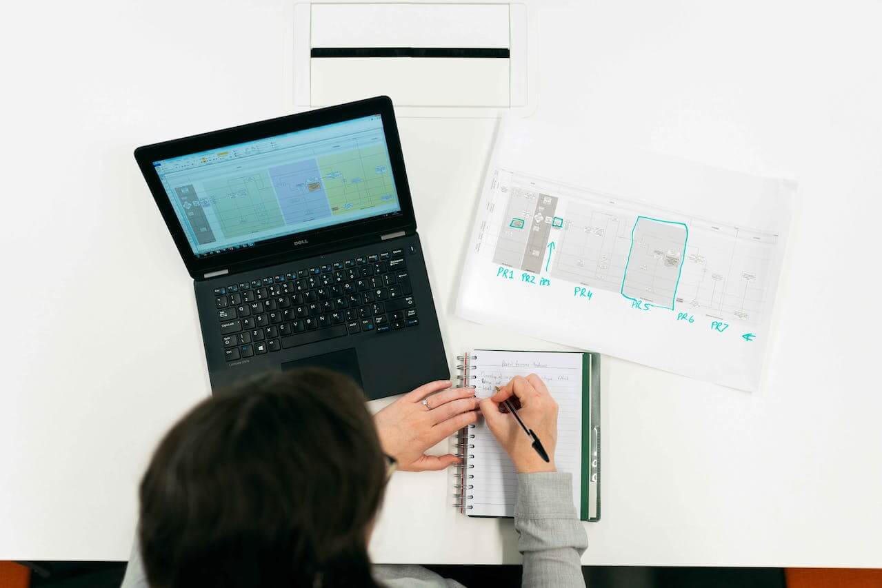 Ingegnere mentre progetta un sistema innovativo utilizzando fogli di carta e un pc.