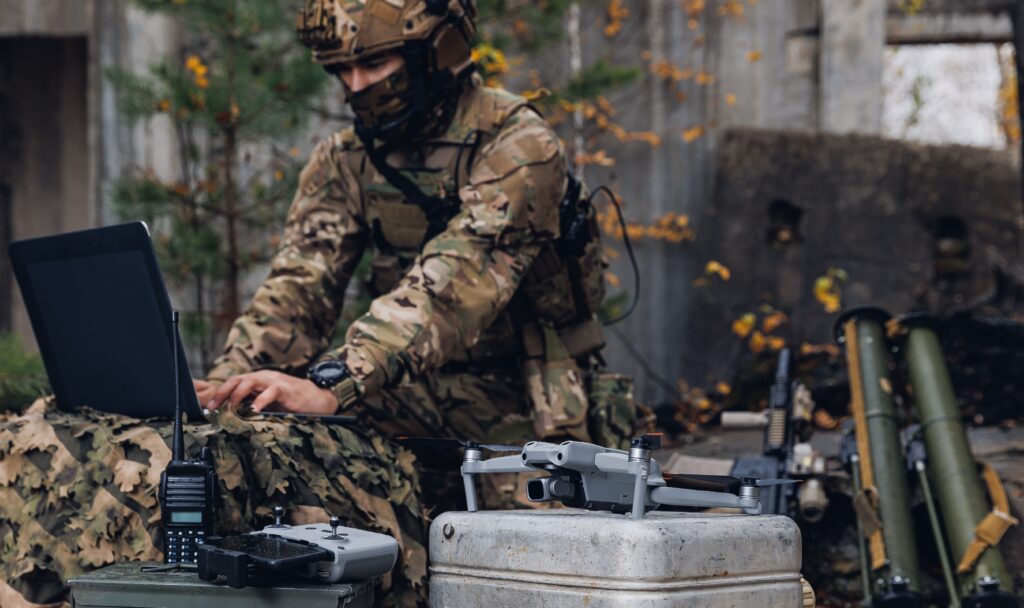 Soldato in uniforme mimetica mentre sta programmando gli strumenti tecnologici da ricognizione.