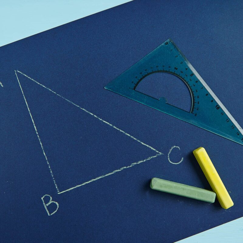 Cartoncino blu scuro con sopra il disegno di un triangolo rettangolo realizzato con una squadra e due gessetti colorati.