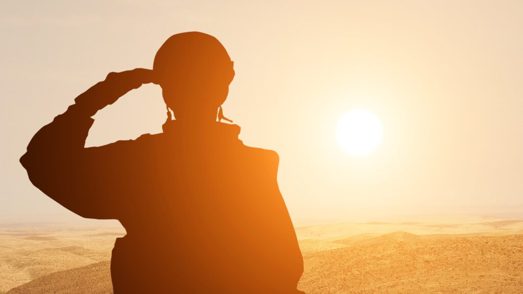 Soldato nella posa del saluto mentre guarda l'orizzonte all'ora del tramonto.