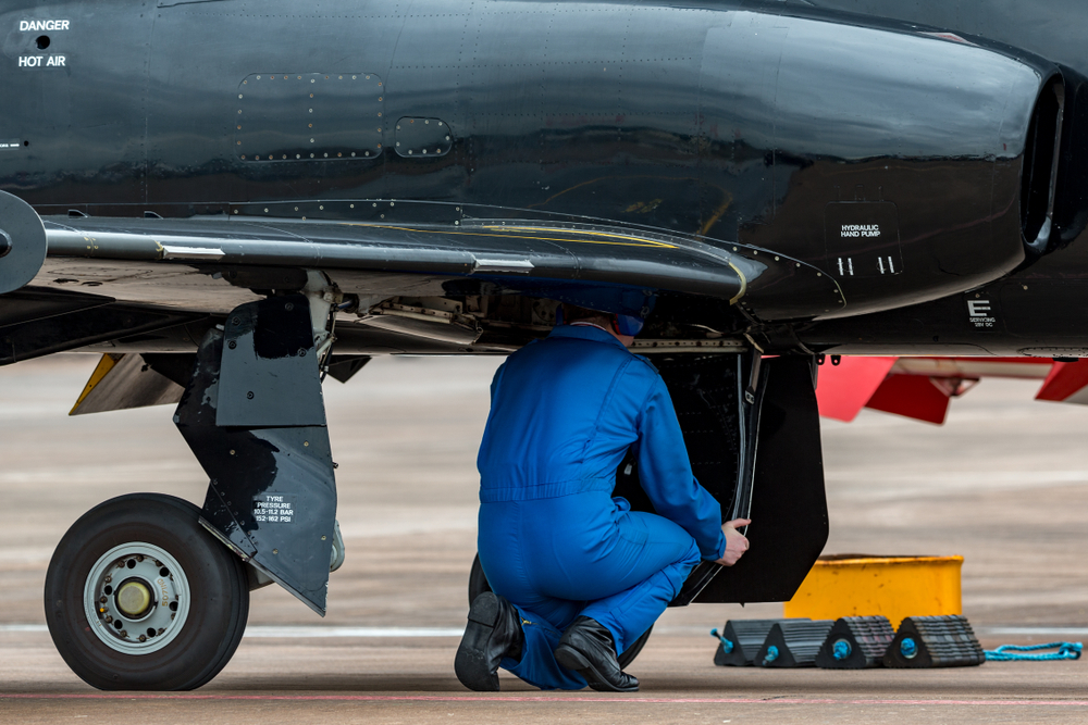 Ingegnere aeronautico al lavoro nel vano carrello di un aereo militare.