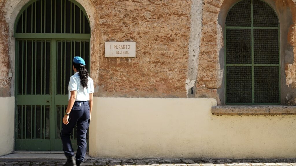 Membro della Polizia Penitenziaria mentre pattugli a piedi il perimetro di un carcere.