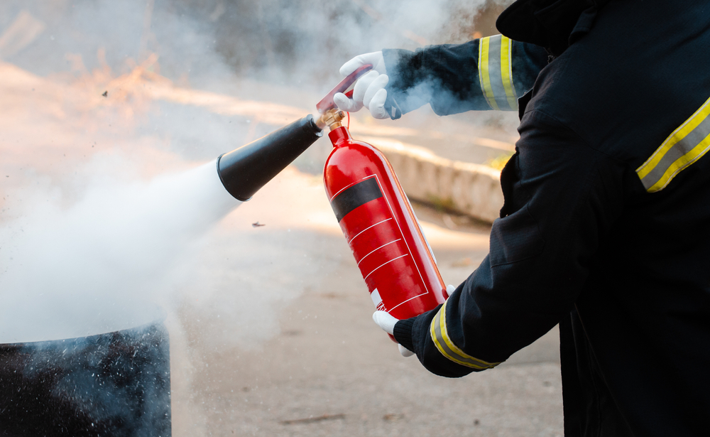 Vigile del fuoco che sta eseguendo esercizi con un estintore, praticando tecniche di spegnimento degli incendi.