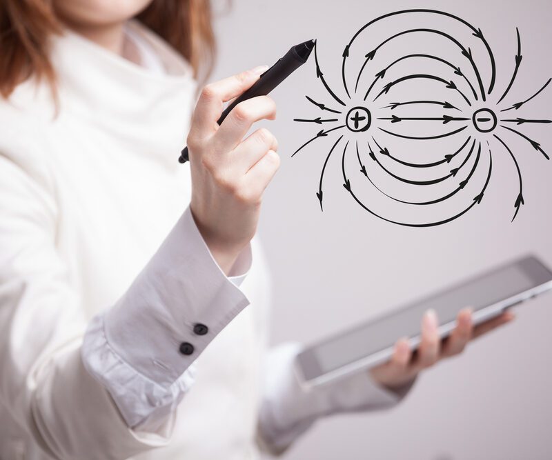 Giovane insegnante di fisica mentre disegna un diagramma dell'elettricità su una lavagna.