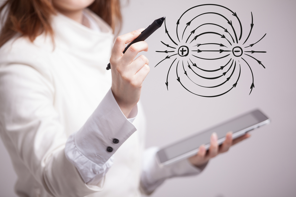 Giovane insegnante di fisica mentre disegna un diagramma dell'elettricità su una lavagna.