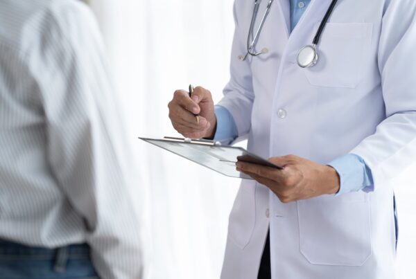 Guardia medica mentre annota su un blocco note i sintomi di un paziente.