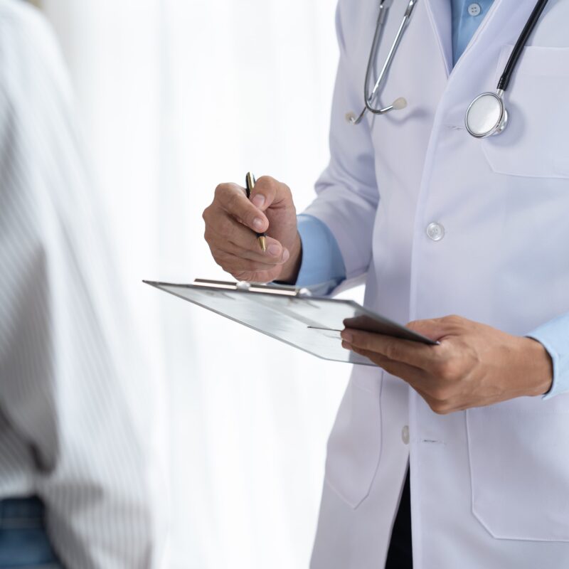 Guardia medica mentre annota su un blocco note i sintomi di un paziente.