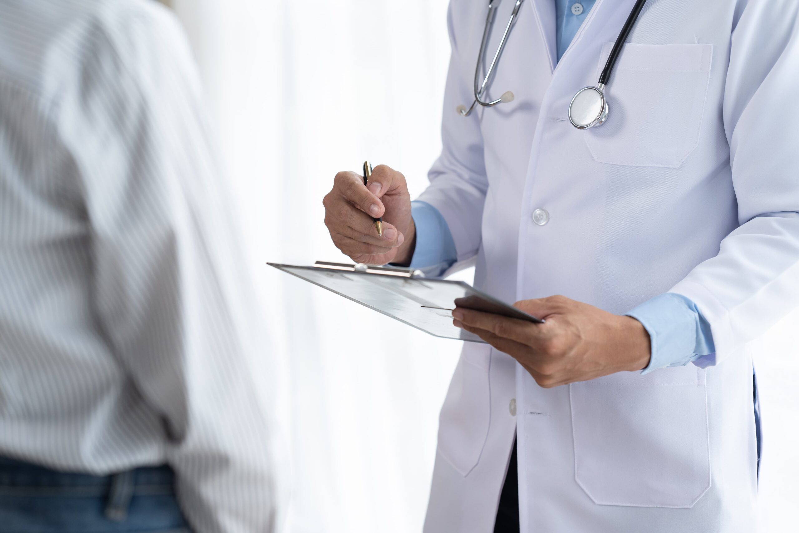 Guardia medica mentre annota su un blocco note i sintomi di un paziente.