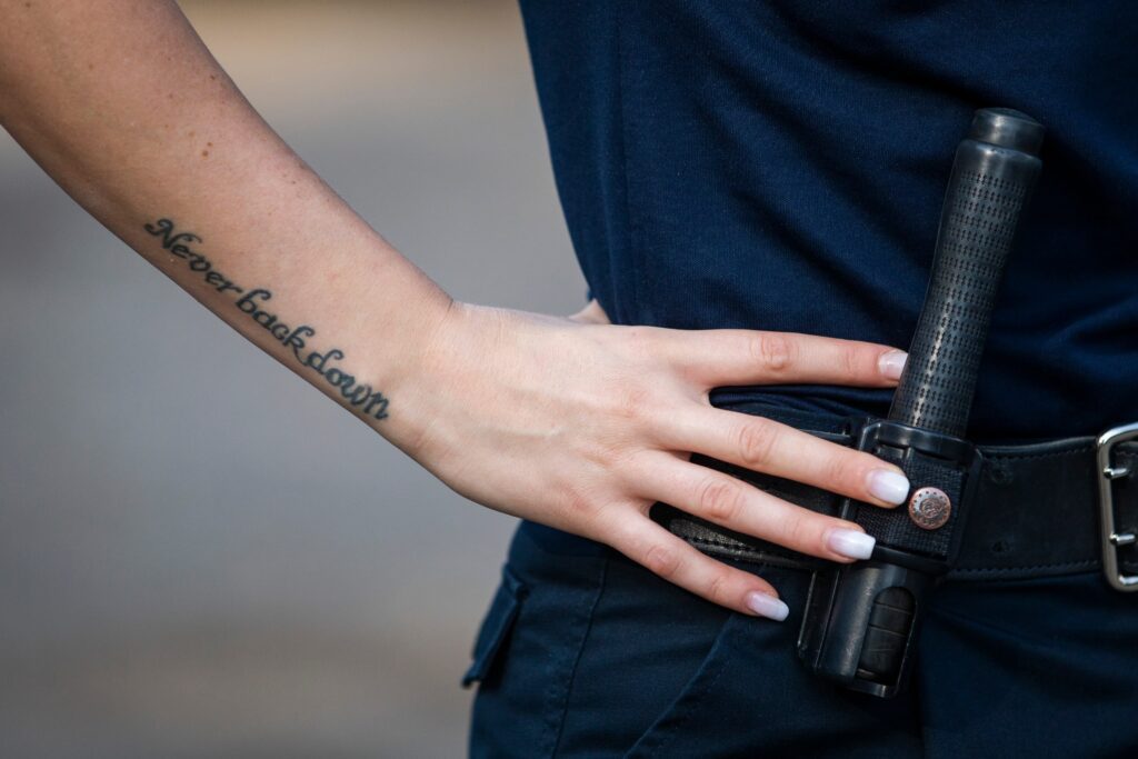 Tatuaggio con frase sul braccio di un poliziotto in pattuglia.