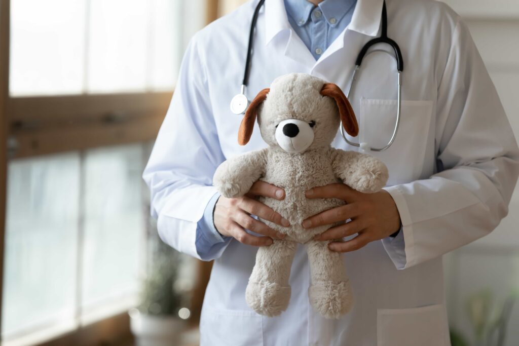 Medico con specializzazione in pediatria mentre aspetta i pazienti con un peluche in mano.