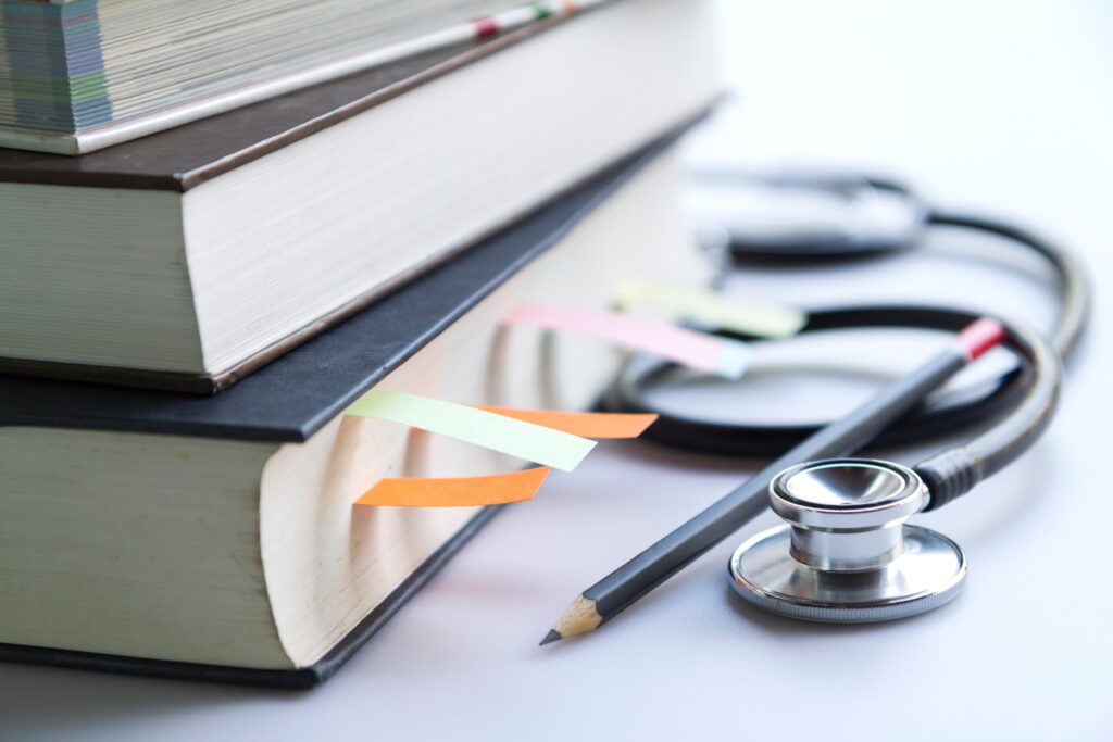 Libri sulle materie del Concorso SSM. Di fianco ai libri ci sono uno stetoscopio e una matita.