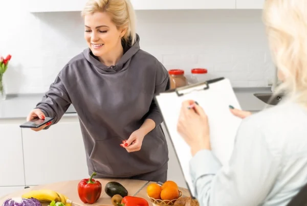 una signora in cucina si fa spiegare come diventare nutrizionista mentre fotografa del cibo su un tavolo