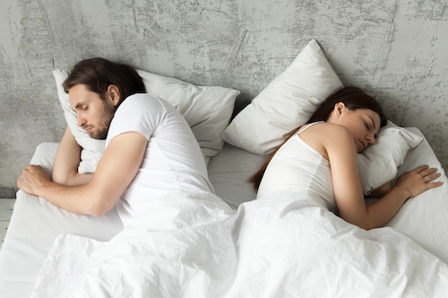 una coppia dorme separata in un letto 