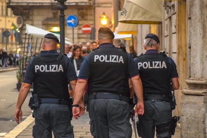 Tre agenti della Polizia di Stato italiana in divisa durante il servizio di pattugliamento in città mostrano come diventare poliziotto in Italia