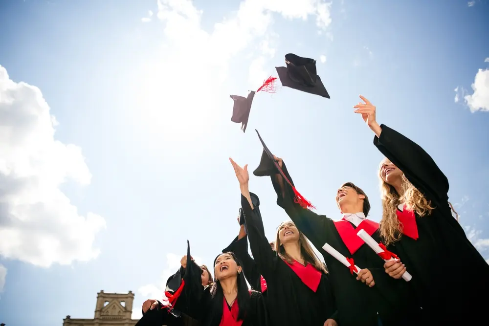 gruppo di laureati lancia il cappello in aria per festeggiare di essersi laureati in una delle università più richieste in italia